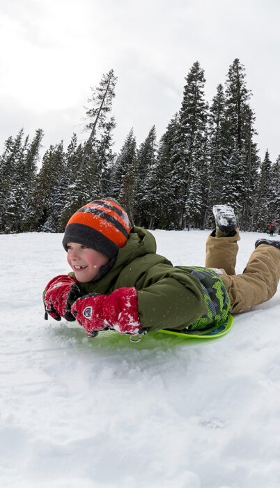 Kid sledding the hill at Wanoga Son-Park in Bend, Oregon.