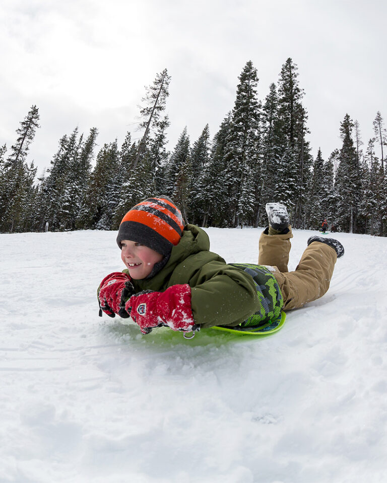 Kid sledding the hill at Wanoga Son-Park in Bend, Oregon.
