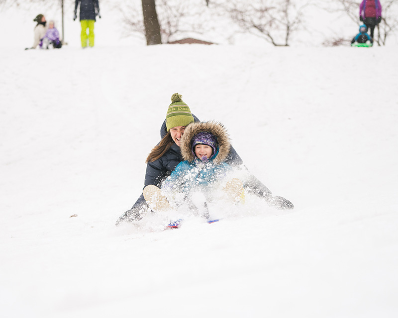 A mom and child are sledding in a park in Downtown bend, Oregon. 
