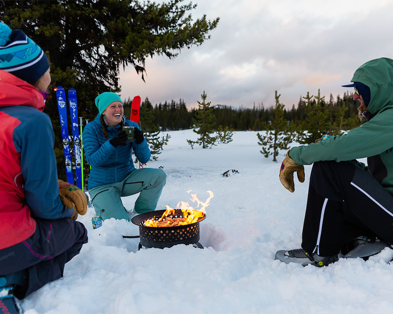 A group relaxes by the fire after a day of winter recreation in the Oregon backcountry. 