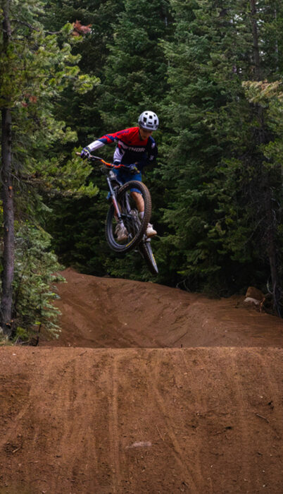 A mountain biker catches air off a jump on the Wanoga downhill trails near Bend, Oregon, showcasing the flow and features of the region’s gravity-style mountain biking terrain.