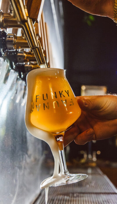 A golden Oregon wild yeast beer being poured at Funky Fauna Artisan Ales, a new brewery in Bend crafting Belgian-style saisons and farmhouse ales.