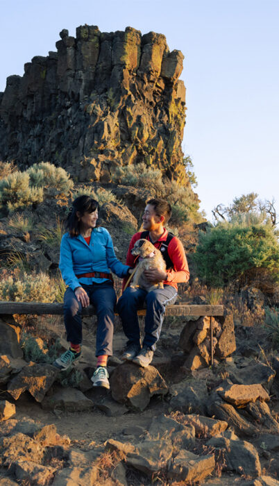 Couple with their dog enjoying golden-hour views on a high-desert hike near Bend, Oregon during spring — a classic spring in Bend Oregon itinerary blending best spring skiing and hiking with scenic canyon trails.