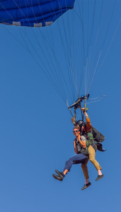 Tandem skydivers descending under a blue parachute against a clear blue sky in Bend, Oregon, capturing an adventurous Central Oregon outdoor experience.