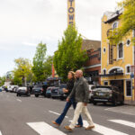 A couple crosses a downtown Bend street in front of the Tower Theatre on a sunny summer day.