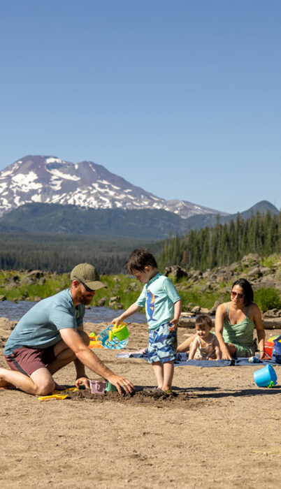 A family plays in the sand at Elk Lake with South Sister mountain in the background, Bend Oregon